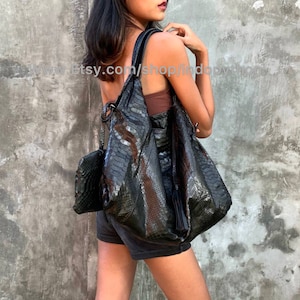 May include: A black snakeskin tote bag with a tassel. The bag has a large, slouchy shape and is made of genuine leather.