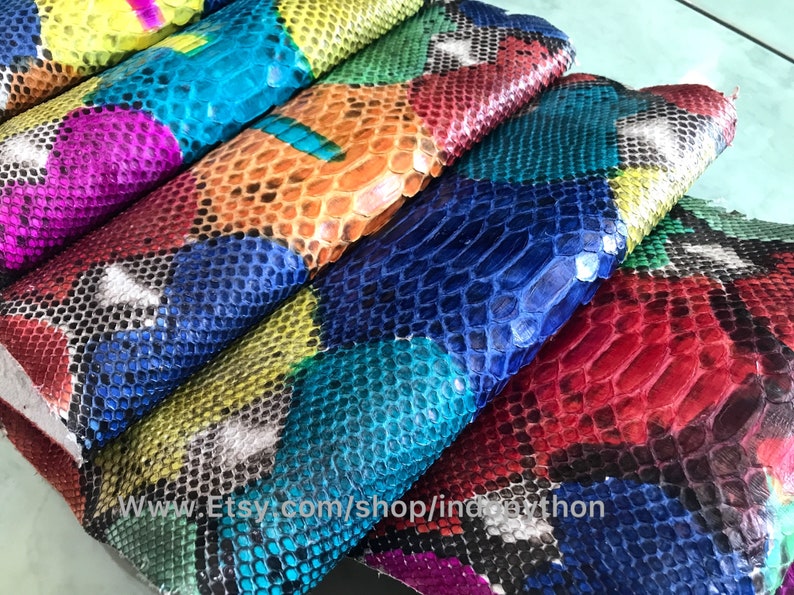 May include: Close-up of colorful python skin leather. The leather is cut into squares and arranged in a patchwork pattern. The colors include red, blue, green, yellow, and black.