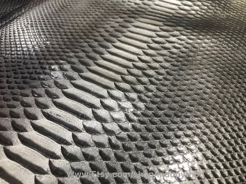 May include: Close-up of a silver snakeskin texture with a subtle gradient from dark to light. The scales are embossed and have a shiny finish.
