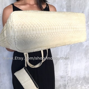 May include: A white python leather tote bag with a matching smaller clutch. The bag has a textured, snakeskin pattern.