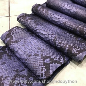May include: A stack of blue python leather hides with a black pattern. The leather is soft and supple, and it would be perfect for making a variety of items, such as bags, wallets, and belts.