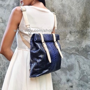 May include: A blue snakeskin backpack with white leather straps and buckles. The backpack is being worn by a person. The text "www.etsy.com/shop/snappyPython" is visible on the image.