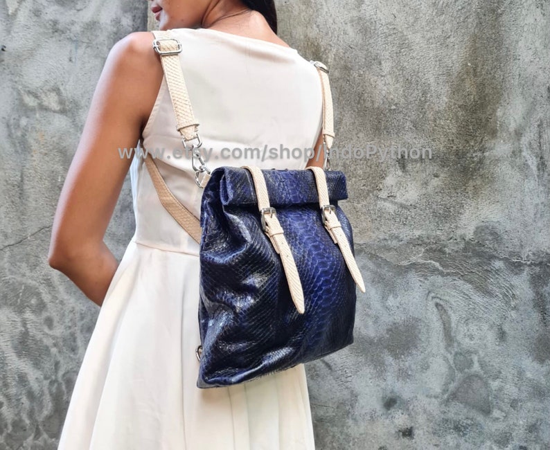 May include: A blue snakeskin backpack with white leather straps and buckles. The backpack is being worn by a person. The text "www.etsy.com/shop/snappyPython" is visible on the image.