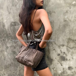 Könnte beinhalten: Eine braune Schlangenleder-Tragetasche mit einem oberen Griff. Die Tasche wird von einer Person getragen, die ein silbernes Oberteil und schwarze Shorts trägt. Der Text "www.Etsy.com/shop/indopython" ist im Bild sichtbar.