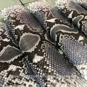 May include: Close-up of several pieces of gray and white snakeskin. The skin has a textured pattern and is folded in a stack.