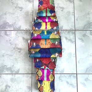 May include: A stack of colorful python skins, each with a unique pattern. The skins are arranged vertically, with the top skin being red and the bottom skin being orange. The skins are all different sizes and shapes, but they are all cut to the same length. The skins are all very vibrant and colorful, and they would be perfect for a variety of crafting projects.