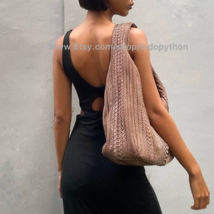 Może przedstawiać: Kobieta w czarnej, bezrękawnikowej sukience z wycięciem na plecach nosi dużą, brązową, teksturalną torebkę. Torebka ma luźny, swobodny styl.