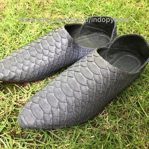 Puede incluir: Un par de zapatos de cuero gris con estampado de piel de serpiente. Los zapatos tienen una punta puntiaguda y un diseño de deslizamiento.