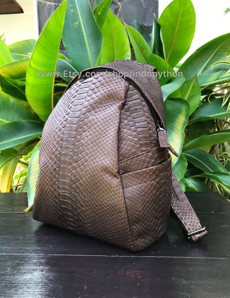 May include: A brown backpack with a snakeskin pattern. The bag has a zippered closure and adjustable straps. The text "www.etsy.com/shop/indopython" is visible on the image.