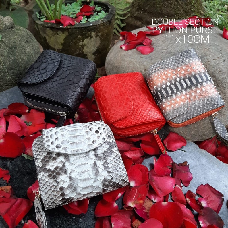 K&ouml;nnte beinhalten: Vier verschiedene Python-Leder-Geldb&ouml;rsen mit Rei&szlig;verschl&uuml;ssen. Die Geldb&ouml;rsen sind rot, schwarz, grau und braun. Die Geldb&ouml;rsen sind auf einem Bett aus roten Rosenbl&auml;ttern angeordnet. Der Text "DOUBLE SECTION PYTHON PURSE 11X10CM" wird &uuml;ber den Geldb&ouml;rsen angezeigt.