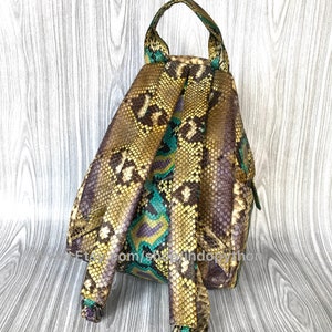 Peut inclure: Un petit sac &agrave; dos en cuir de python vert, jaune et violet. Le sac &agrave; dos a une poign&eacute;e sup&eacute;rieure et des bretelles r&eacute;glables.