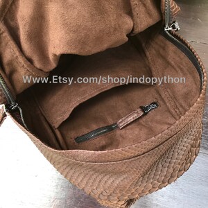 May include: Brown backpack with a textured snakeskin pattern. The bag has a zippered closure and a front pocket. The interior is a lighter brown color. The Etsy shop name is visible in the image.