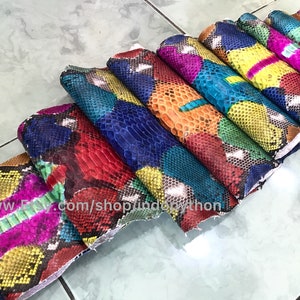 May include: A stack of colorful python skin hides, each with a unique pattern. The hides are arranged in a fan shape, with the largest hide at the bottom and the smallest hide at the top. The hides are all different colors, including red, blue, green, yellow, and orange.