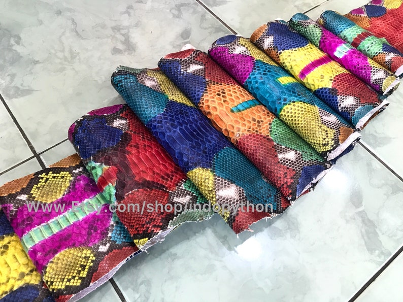 May include: A stack of colorful python skin hides, each with a unique pattern. The hides are arranged in a fan shape, with the largest hide at the bottom and the smallest hide at the top. The hides are all different colors, including red, blue, green, yellow, and orange.