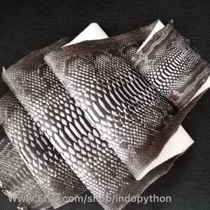 Może przedstawiać: Cztery kawałki czarno-białej sk&oacute;ry pytona, ułożone jeden na drugim. Sk&oacute;ra ma fakturowany wz&oacute;r. Sk&oacute;ra leży na białym tle. www.Etsy.com/shop/indopython