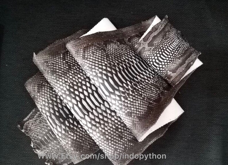 Może przedstawiać: Cztery kawałki czarno-białej sk&oacute;ry pytona, ułożone jeden na drugim. Sk&oacute;ra ma fakturowany wz&oacute;r. Sk&oacute;ra leży na białym tle. www.Etsy.com/shop/indopython