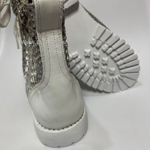 May include: White leather ankle boots with a snakeskin pattern on the back of the boot. The boots have a white rubber sole.
