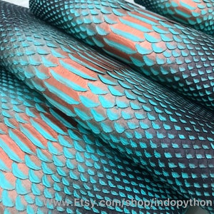Op de afbeelding: Close-up van een stapel turquoise en koperkleurige pythonskin. De schubben zijn zichtbaar en de huid is glad en glanzend. www.Etsy.com/shop/indopython