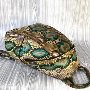Peut inclure: Un sac &agrave; dos en cuir de serpent brun et vert avec une fermeture &eacute;clair et une poign&eacute;e sup&eacute;rieure. Le sac &agrave; dos a un motif unique et est fait de cuir v&eacute;ritable.