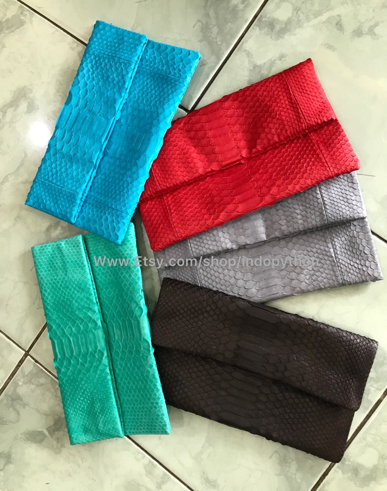 Peut inclure: Plusieurs pochettes de soir&eacute;e rectangulaires, de couleurs turquoise, rouge, grise, marron et vert d'eau. Chaque pochette pr&eacute;sente un rabat et une texture &agrave; motifs d'&eacute;cailles. Le texte sur l'image indique : www.etsy.com/shop/indopython. Elles sont faites d'un mat&eacute;riau semblable &agrave; de la peau de serpent.