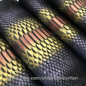 May include: Close-up of exotic leather with a scale pattern. The leather has a color gradient from dark purple to gold and copper. The scales are small and tightly packed, creating a textured surface. The Etsy shop URL is visible at the bottom.
