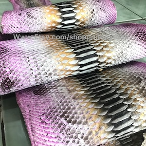 Könnte beinhalten: Nahaufnahme eines Stapels aus rosa, goldfarbenem und schwarzem Schlangenleder. Das Leder hat ein strukturiertes, schuppiges Muster. Der Text "www.Etsy.com/shop/7Indigodesigns" ist auf dem Leder sichtbar.