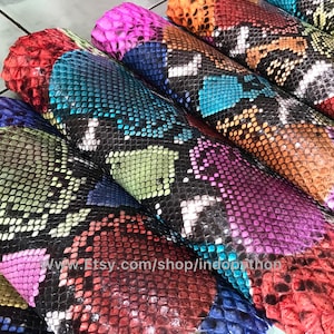 以下が含まれることがあります： さまざまなパターンとテクスチャを備えた、カラフルなニシキヘビの皮の詰め合わせ。皮は一列に並べられており、最も鮮やかな色は上部に、暗い色は下部に配置されています。皮はすべて長方形にカットされており、クラフトプロジェクトに使用できる状態です。