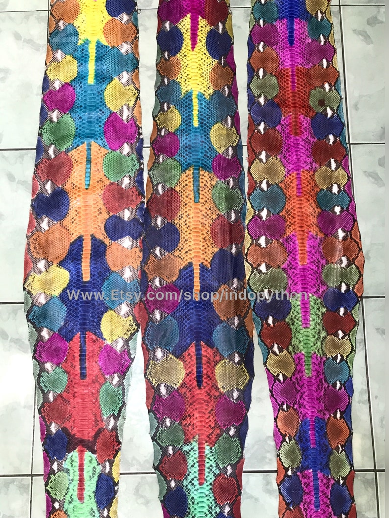 May include: Three colorful python skins with a variety of colors, including red, blue, green, yellow, and orange. The skins are arranged vertically and have a textured pattern. The text "www.Etsy.com/shop/indopython" is visible at the bottom of the image.