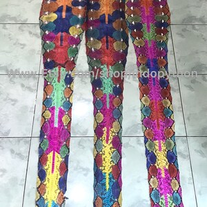 May include: Three long strips of colorful snakeskin, each with a different pattern. The skins are arranged vertically and are all about the same length. The colors are bright and vibrant, including red, orange, yellow, green, blue, and purple.