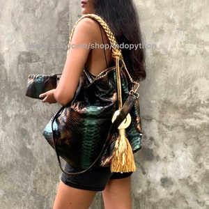 May include: A green and brown snakeskin handbag with a gold tassel and braided strap. The bag has a matching snakeskin clutch.