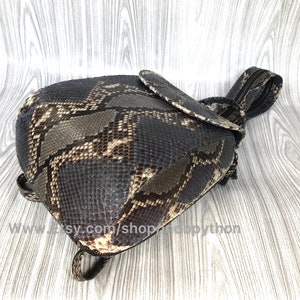 Pu&ograve; includere: Uno zaino piccolo in pelle di pitone marrone e beige con chiusura a zip. Lo zaino ha un'unica spallacciatura ed &egrave; realizzato in vera pelle di pitone.