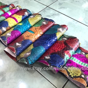 May include: A stack of colorful python skin hides, each piece featuring a unique pattern of scales. The hides are arranged in a rainbow of colors, including red, blue, green, yellow, and pink.