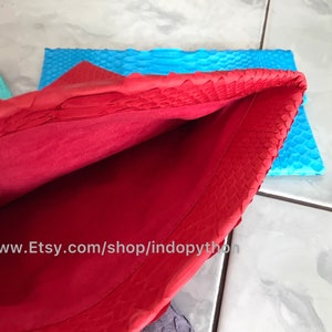 Peut inclure: Un sac &agrave; main rouge en cuir avec un ext&eacute;rieur textur&eacute;, ouvert pour r&eacute;v&eacute;ler un int&eacute;rieur rouge. Un morceau de cuir bleu est visible en arri&egrave;re-plan. L'URL de la boutique Etsy est visible en bas de l'image.