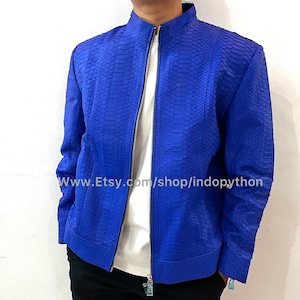 Könnte beinhalten: Eine leuchtend blaue Jacke mit strukturiertem Schlangenmuster. Sie hat einen Stehkragen, einen durchgehenden Reißverschluss und lange Ärmel. Die Etsy-Shop-URL ist im Bild sichtbar. Diese Jacke ist eine stilvolle Oberbekleidung.