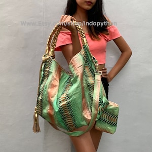 May include: A green and orange snakeskin-patterned handbag with a gold chain strap and tassel. The bag has a top handle and a shoulder strap.