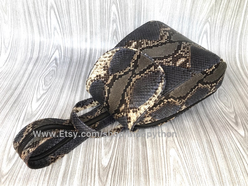 Pu&ograve; includere: Una piccola borsa a mano in pelle di serpente nera e marrone con chiusura a zip e tracolla. La borsa ha una patta con chiusura a zip. La borsa &egrave; su una superficie di legno. www.Etsy.com/shop/SnappyPython