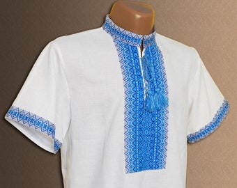 Peut inclure: Chemise à manches courtes blanche avec des motifs géométriques brodés bleus sur le devant.