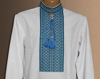 Peut inclure: Une chemise blanche à manches longues avec un motif brodé bleu et noir sur le devant. La chemise est de style ukrainien traditionnel.