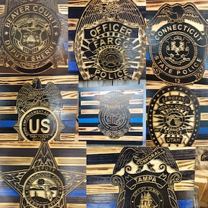 May include: A collage of nine wooden plaques with different law enforcement badges. The badges are all in a similar style, with a black and brown wood background and a gold-colored design. The badges feature the names of different law enforcement agencies, including "Beaver County Deputy Sheriff", "Officer Fargo", "Connecticut State Police", "Drug Enforcement Administration", "Trooper", "Sergeant North Ogden Police", "Hillsborough County Sheriff's Office", and "Corporal Tampa".