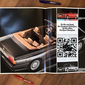 May include: A black BMW convertible with a tan interior and a number plate that reads "MNM 5707". The car is photographed from above and the roof is down. The image includes text that reads "On the one hand, the European Champion. On the other, the Open Champion."
