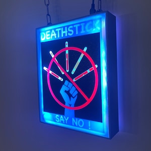 May include: A blue and white neon sign with the text "DEATHSTICK" and a red circle with a fist and crossed out cigarettes. The text "SAY NO!" is below the circle.