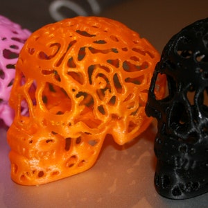 Pu&ograve; includere: Tre sculture di teschio decorative, una rosa, una arancione e una nera. Ogni teschio &egrave; realizzato in un materiale traslucido con un design dettagliato e intricato.