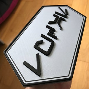 Könnte beinhalten: Ein weißes Schild mit schwarzem Rand und dem Wort "DRIVE" in schwarzen, erhabenen Buchstaben.