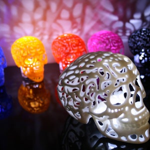 Pu&ograve; includere: Un set di sei lampade decorative a forma di teschio in vari colori, tra cui blu, arancione, rosso, rosa, nero e bianco. Le lampade sono realizzate in un materiale traslucido e hanno un design delicato e intricato.