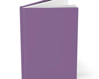 May include: A hardcover journal with a solid purple cover. The journal is slightly open, revealing the white pages inside. The spine is visible, and the book is set against a white background.