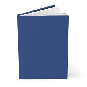 May include: A hardcover journal with a solid navy blue cover. The journal is slightly open, revealing the white pages inside. The spine is visible, and the book is positioned upright, suggesting it's ready for use. The overall aesthetic is clean and simple.