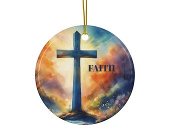 Op de afbeelding: Ronde keramische ornament met een aquarelontwerp met een blauw kruis tegen een achtergrond van oranje en blauwe tinten. Het woord "FAITH" is in marineblauw gedrukt. Een gouden draad is bevestigd om op te hangen.