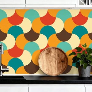 May include: A kitchen splashback with a retro design in orange, teal, brown, and cream. A wooden serving tray, a potted plant, and a black coffee machine are on the countertop.