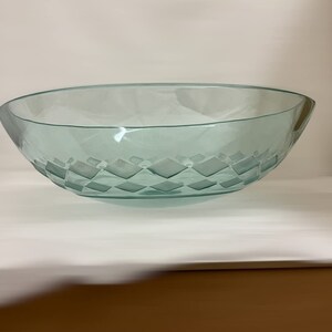 May include: A clear glass serving bowl with a diamond pattern etched into the bottom. The bowl is oval shaped and has a slight lip around the edge.