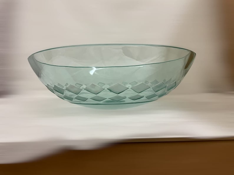 May include: A clear glass serving bowl with a diamond pattern etched into the bottom. The bowl is oval shaped and has a slight lip around the edge.